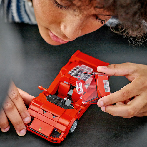 Criança montando o LEGO Speed Champions Ferrari F40 76934, encaixando o para-brisa transparente do cockpit do supercarro vermelho