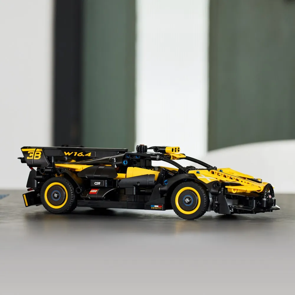Bugatti Bolide LEGO Technic 42151 montado em vista de perfil sobre superfície clara, preto e amarelo com aerofólio em X