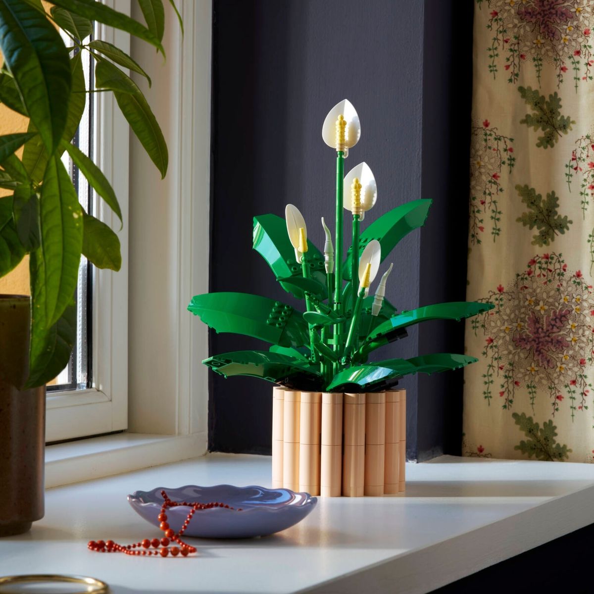 Lírio da Paz LEGO 11504 ao lado de janela com plantas e cortina floral