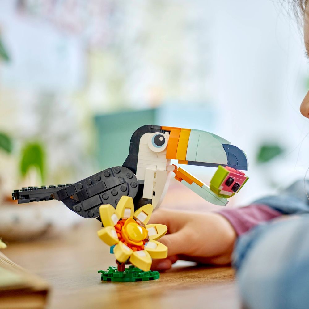 Criança brincando com LEGO Creator 31173 Tucano Tropical sobre a mesa