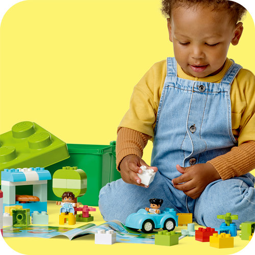 Criança brincando com o carrinho, casinha e peças do LEGO DUPLO Caixa de Peças