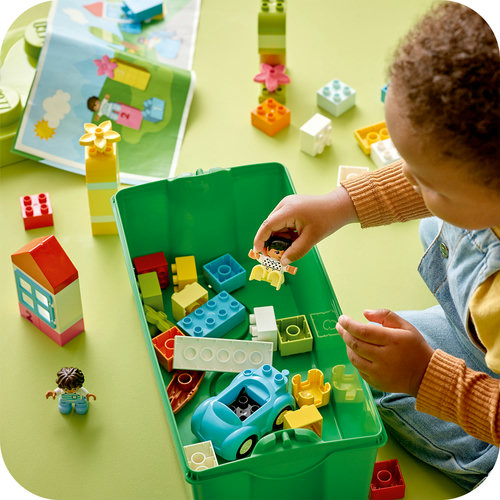 Criança brincando com peças LEGO DUPLO dentro da caixa verde