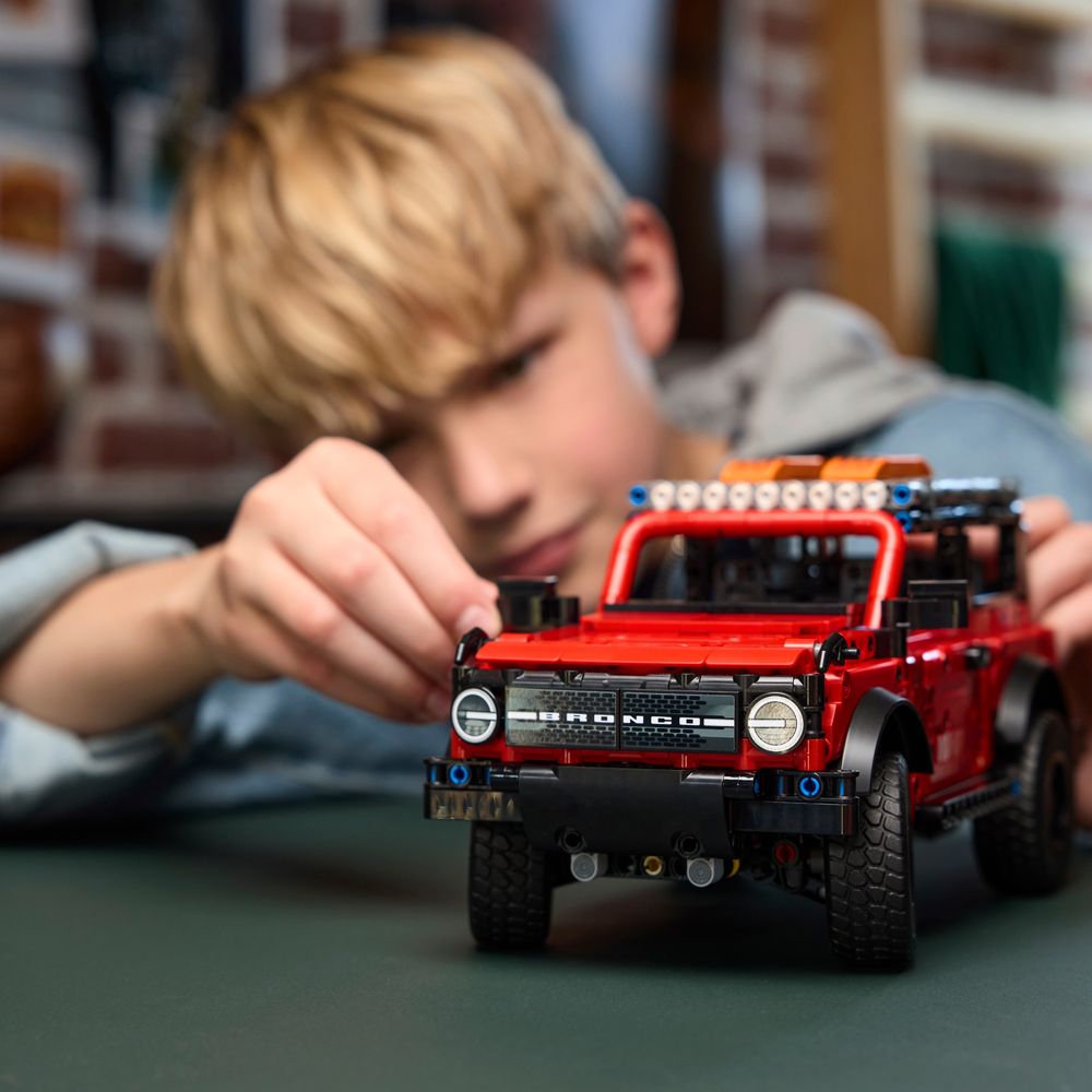 Criança brincando com LEGO Technic 42213 Ford Bronco na mesa