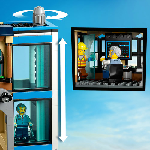 Close-up do elevador funcional da estação LEGO 60469: manivela externa, cabine de vidro com viajante e detalhe interno mostrando o operário consertando
